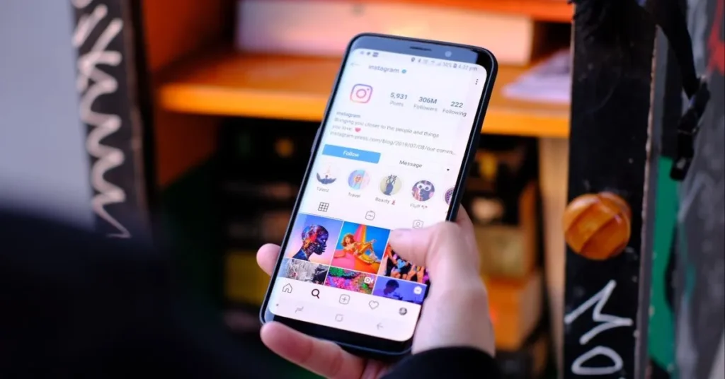 Pessoa segurando um smartphone mostrando o perfil oficial do Instagram, ilustrando um perfil otimizado com destaques e visual profissional.